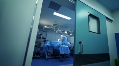 Cerrahi aletleri olan profesyonel doktorlar. Steril eldivenli cerrahlar modern tıbbi aletlerle çalışırlar. Ameliyat sağlayan cerrahlar. Kapının arkasındaki seçici odak.