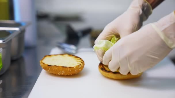 Ruce Latexových Rukavicích Dávají Salát Smaženou Housku Dělám Burger Bílém — Stock video