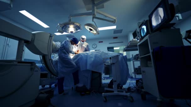 Specjaliści Nowoczesnej Sali Operacyjnej Lekarze Wykonują Operację Patrząc Proces Monitorze — Wideo stockowe