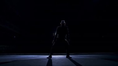 Karanlıkta sahnede kostümlü son sınıf öğrencisi. Tiyatrodaki gösteri sırasında şapkalı aktif bir adam sahnede dans ediyor..