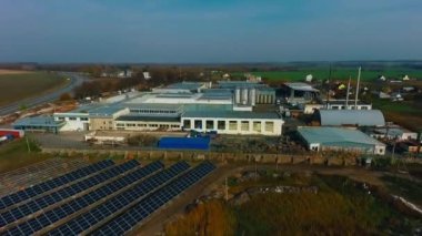 Mavi güneş panelleri ve üzerinde mavi gökyüzü olan imalat fabrikası. Yenilenebilir enerji için fotovoltaik modüllerin arka planı. İnsansız hava aracından video.
