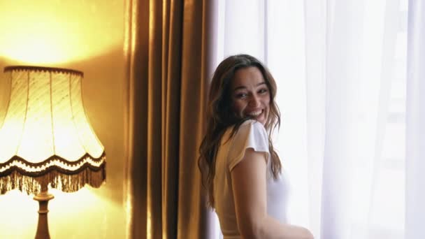 Genç Mutlu Gülümseyen Kadın Bir Otel Odasının Penceresinden Dışarı Bakıyor — Stok video