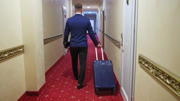 Seorang Pria Dengan Koper Berjalan Menyusuri Lorong Hotel Karpet Merah — Stok Video