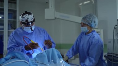 Yeni tıbbi ekipmanların yardımıyla cerrahi işlem. Ameliyathanede çağdaş ekipmanlar var. Mavi üniformalı uzmanlar bir operasyon düzenliyor..