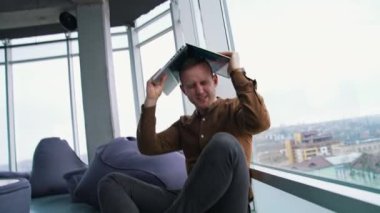 Genç bir adam dizüstü bilgisayarla yerde oturuyor. İnsanın iş stresi konsepti