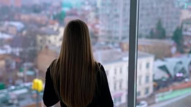 Güzel bir kadın gözlük takıyor, cep telefonu kullanıyor ve kahve içiyor.