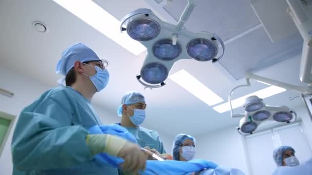 医者のグループは患者に手術を行う 手術室で働く制服やマスクの外科医 — ストック動画