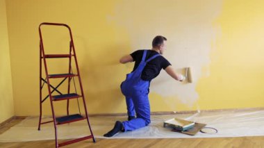 Odada duvar boyayan genç bir işçi. Onarım, bina ve ev konsepti.