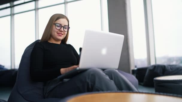 ノートパソコンで作業するメガネを持つ若い美しい女性 — ストック動画