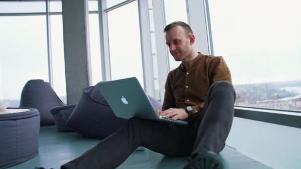 Młody Człowiek Laptopem Siedzący Podłodze Przy Oknie — Wideo stockowe