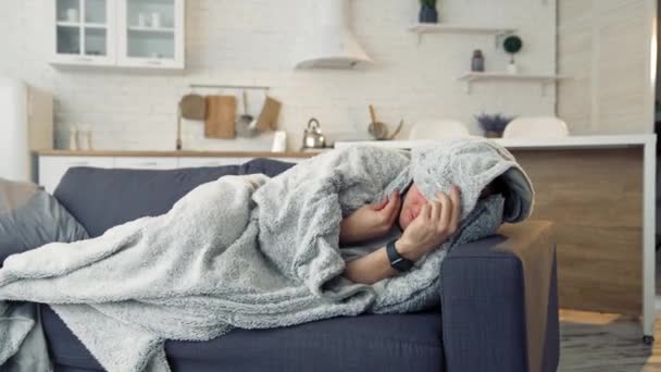 寒さとインフルエンザの症状で自宅のソファーで病気を感じる男性 パンデミック — ストック動画