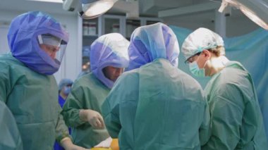 Ameliyathane ve ameliyat devam ediyor. Tıbbi ekip, parlak modern ameliyathanede cerrahi operasyon gerçekleştiriyor.