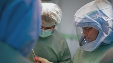 Ameliyatta. Hastane ameliyathanesinde tıbbi ekip operasyon yapıyor. Cerrahi aletlerle çalışmak.