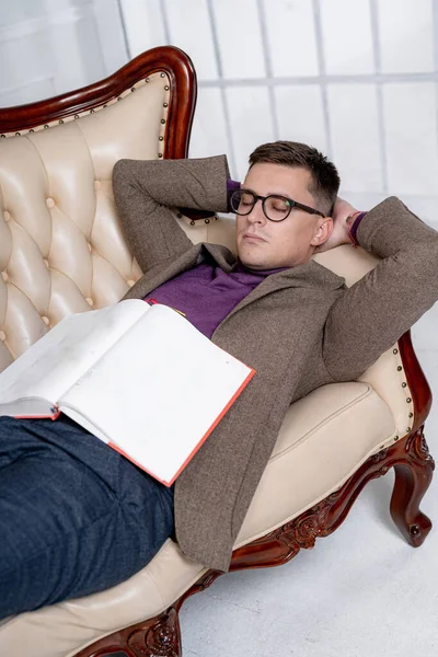 A man laying on a couch with a book