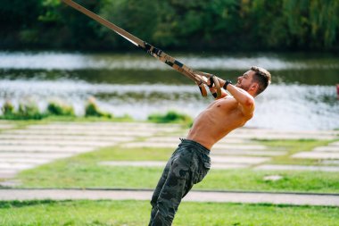 Kaslı adam çalışıyor. Açık havada idman yapan üstsüz bir erkek..