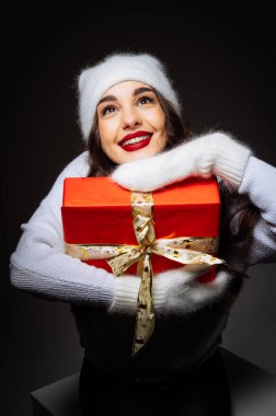 Elinde kırmızı bir kutu tutan Noel Baba şapkalı bir kadın. Kırmızı Kutulu Şenlikli Kadın