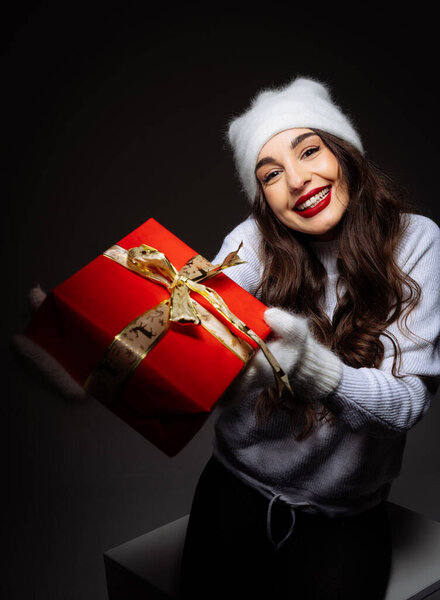 A woman in a santa hat holding a red gift box. A Festive Woman with a Gift Box