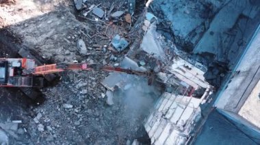 Bir kazıcının uzun pençesi binanın beton kısımlarını yok eder. Depremden sonra bina yıkıldı. Yıkılmış binaların kalıntılarıyla çalışan kazıcıların manzarası.