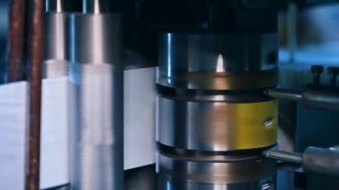 Parlayan metal dikey şaft hızla dönüyor ve gelecekteki bebek bezleri için bir rulo fiber taşıyor. Fabrikada bebek bezi üretiyorum..