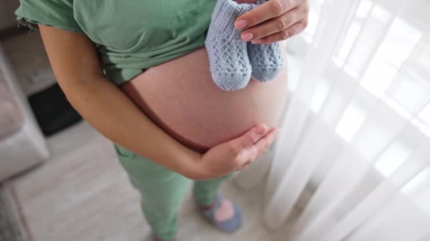 Mujer Embarazada Sosteniendo Dos Bonitos Botines Bebé Sobre Vientre Pone — Vídeos de Stock
