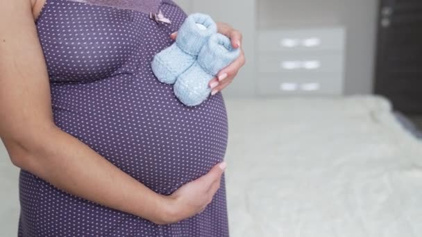 Gecelikli Beyaz Hamile Bir Kadın Karnında Küçük Bebek Çorapları Tutuyor — Stok video