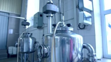 Ayarlanmış boruları ve boruları olan iki küçük sarnıç. Süt fabrikasının penceresinin önüne metal depoları yerleştirildi. Kapat..