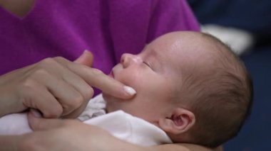 Annesinin kucağındaki güzel bebek tatlı tatlı uyuyor. Anne, oğlunun çenesine, burnuna ve yanaklarına dokunarak uyandırmaya çalışıyor. Tatlı çocuk uyanmak istemiyor..