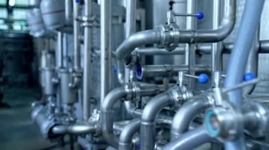 Modern süt fabrikasında sayısız boru birbirleriyle kesişiyor. Valfları ve muslukları olan boru hatları. Yavaş yavaş mesafeyi kapat.