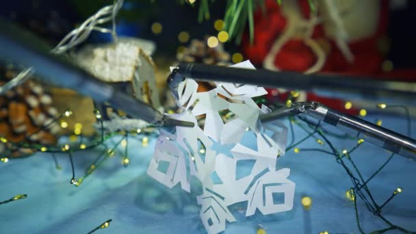 顕微鏡用の2つのロボットアームは 紙のスノーフレークを保持し 3番目のアームは小さな断片を切断します バックグラウンドでの新年の装飾 — ストック動画