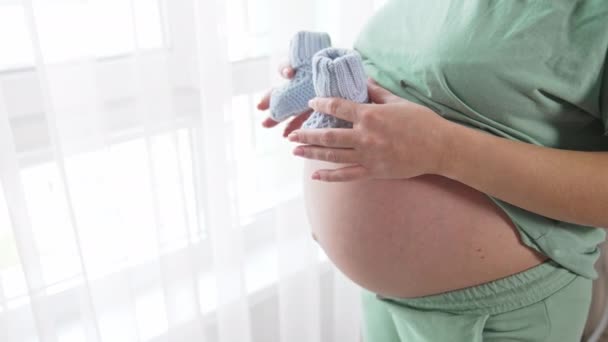 Tanımlanamayan Hamile Bir Kadın Koca Karnının Üstünde Küçük Bebek Çoraplarını — Stok video
