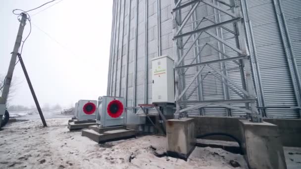 大通风机放置在一个巨大的谷物升降机圆筒外面 从靠近谷物升降机的金属支撑物移动到一个通风机的后面 — 图库视频影像