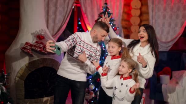 幸せな家族がクリスマスツリーの近くでセルフィーを取ります 美しく装飾された部屋で楽しむ4人の家族 クリスマスと新年のお祝い — ストック動画