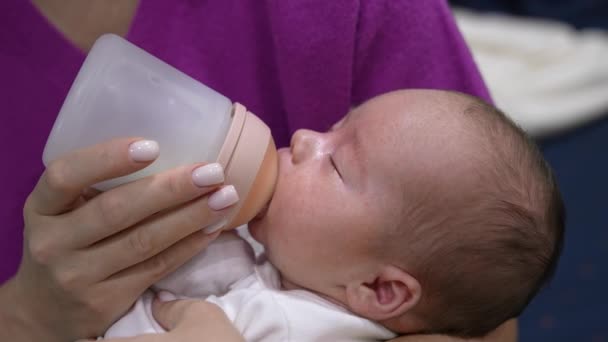 愛する母親が腕に赤ん坊を抱き 瓶からそれを与える 生まれたばかりの子供は おしゃぶりでボトルから餌を与えられている クローズアップ — ストック動画