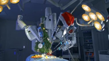 Robot cerrahi makinesi ameliyat masasındaki mandalinaları soyar. Ameliyathanede yüksek teknoloji ekipmanı var ve ışıkları açık. Ameliyathanede Noel süslemeleri.