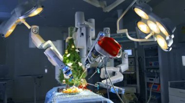 Da Vinci cerrahi sisteminin robot kollarında yeni yıl ağacı. Robotun yardımıyla ufak tefek işler yapabilme olanaklarını gösteriyor. Ameliyat masasında Noel ağacı ve çelenkler.