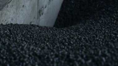 Bastırılmış kömür yığını fırına doğru iniyor. Çimento duvarına küçük kömür parçaları dökülüyor. Kapat..
