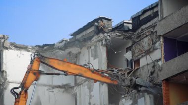 Mavi gökyüzünün altındaki harabeler kazıcı makine tarafından yıkılıyor. Şehrin geleceği için yıkım sürecinde olan yıkılan ev.