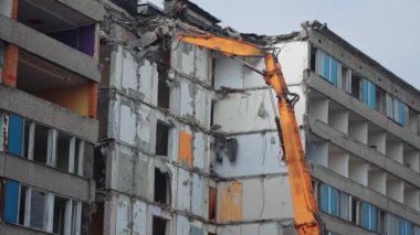 Kazıcının hidrolik pençesiyle en üst katlar yıkıldı. Kazı kovası ile yeni inşaat için eski bina yıkılıyor. Aşağıdan görüntüle.
