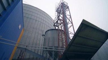 Tanklar, merdivenler ve tahıl depolama fabrikasındaki diğer tesisler. Üzerinde metal merdiven olan büyük bir sarnıca geliyor. Kapat..