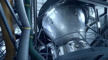 Kalın plastik tüplerin yanında büyük bir mandıra tankı. Kalkmış platformda, temeli sensörlerle duran paslanmaz çelik tank. Aşağıdan çember görünümü.