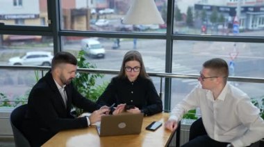 Meslektaşlar panoramik pencerelerin önünde masada oturuyorlar. İş adamları ellerinde cep telefonlarıyla bir şeylerden bahsediyorlar..
