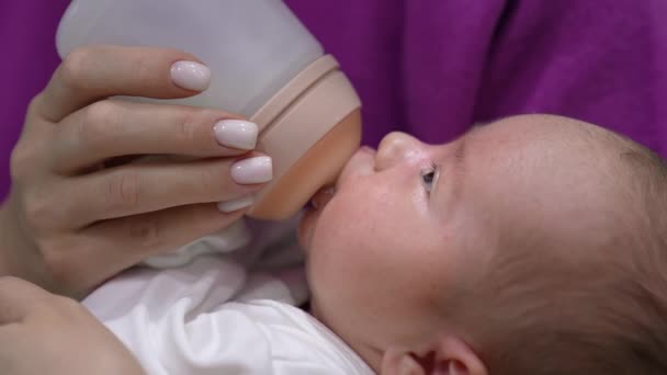 幼い赤ん坊はボトルから母親に餌を与えられています 子供は瓶からミルクを吸い ゆっくりと眠りに落ちる クローズアップ — ストック動画