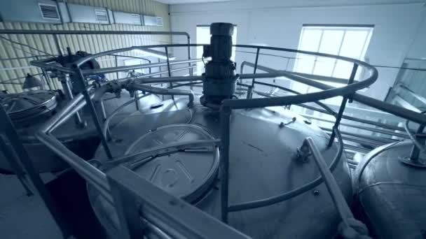 乳製品工場の列に立っている大きな鋼鉄タンク 上からの牛乳のシスターのトップを見てください キャスターの蓋につながる橋からのガイズ — ストック動画