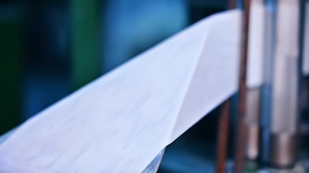 尿布生产企业 用一卷模糊的白丝带制造耐用的尿布紧固件 钢制滚筒之间的白色带子拉紧了 — 图库视频影像