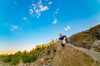 Majestic Rock 'tan Huzurlu Manzaranın Tadını Çıkaran Adam. Büyük bir kayanın üstünde oturan bir adam.
