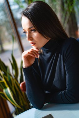 Eli çenesinde bir masada oturan bir kadın.