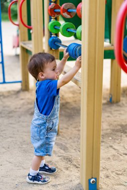 Çocuk parkında neşeli bir çocuk. Bir oyun alanının önünde duran küçük bir çocuk.