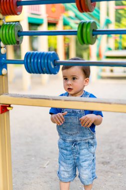 Küçük çocuk oyun sahasında oyun zamanının tadını çıkarıyor. Bir oyun alanının önünde duran küçük bir çocuk.