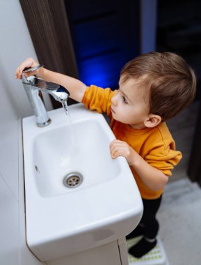 Banyoda Su Eğlencesi Yapan Oyuncu Küçük Çocuk. Banyoda lavaboyla oynayan küçük bir çocuk.