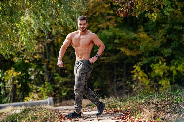 A shirtless man running on a path in the woods